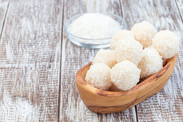 Healthy raw paleo coconut energy balls in a wooden bowl, horizontal, copy space