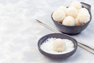 Healthy homemade raw paleo energy coconut balls in ceramic bowl, horizontal, copy space