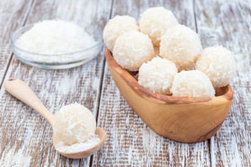 Healthy raw paleo coconut energy balls in wooden bowl, horizontal