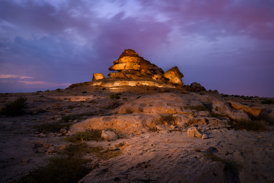 Beautiful view of rock hill also called Dragon Rock illuminated with striking clouds after sunset at Sakhir mountains, Bahrain.