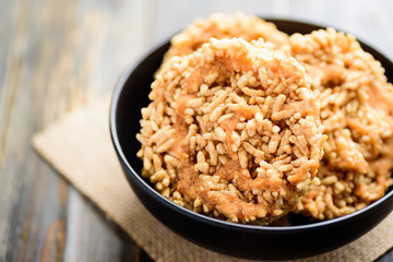 Sweet crispy rice with cane sugar drizzle in a black bowl, Local Thai snack (Khao Tan)
