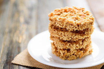 Stack of sweet crispy rice with cane sugar drizzle on white plate, Local Thai snack (Khao Tan)