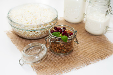 the concept of healthy and proper nutrition. Milk in a jar with a handle, cottage cheese and granola in a jar on a napkin with a mint leaf and cranberries