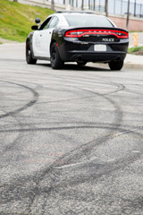 Fototapeta na wymiar Tire marks in the road from cars doing donuts. with a blurred police car in the background. 
