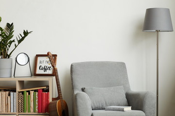 Background image of cozy modern interior with minimal decor items and grey armchair against white wall, copy space above