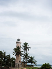 view of the lighthouse with palm trees against the sky in asia