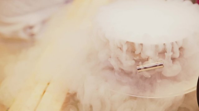 Liquid nitrogen smokes in a gray iron pan bowl with handles