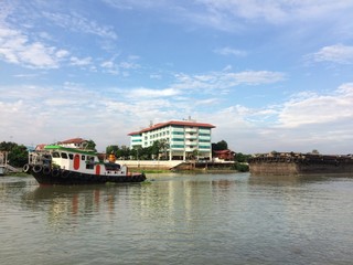 Fototapeta na wymiar Ayutthaya,Thailand-April 19, 2020 : A tug boat is towing the large cargo boat.
