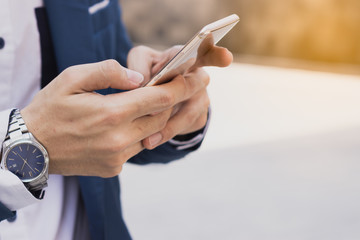 Closeup business man holding and pointing to smartphone in the modern city. Business and finance concept.