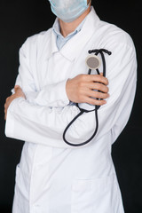 Male Doctor on a black background with a stethoscope in his hands close-up