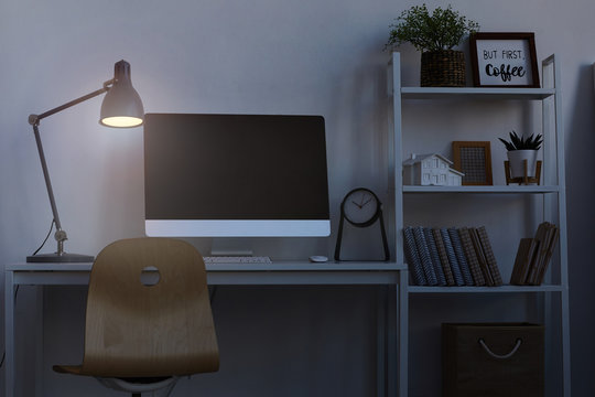 Background image of home office workplace at night, with focus on computer desk lit by dim lamp light, copy space
