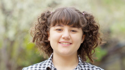 Fototapeta premium Standing alone in outdoor Little girl looking at camera and having fun, smiling, emotions. Close Up Face photo Red camera still. Happy girl portrait.