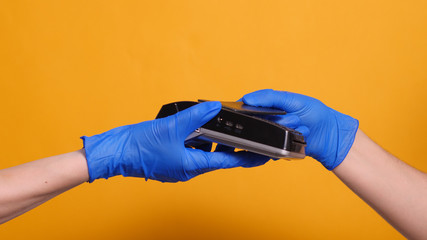 customer in a store applies a credit card to a terminal in blue rubber medical gloves