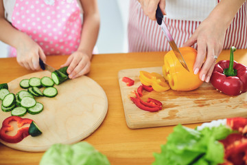 Faceless. Family hands prepare fresh vegetables salad on the table in the kitchen.