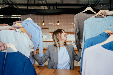 Young stylist looking through set of shirts for fashion shooting