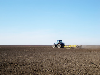 Obraz premium Plowed field by tractor in brown soil on open countryside nature