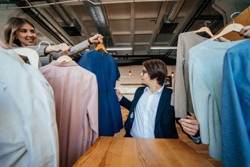 Young stylist looking through set of shirts for fashion shooting