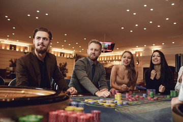 Happy people are betting in gambling at roulette poker in a casino