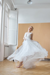 Fototapeta na wymiar Bride is a woman in a light summer wedding dress standing at the window. Blonde girl with perfect hair and beautiful makeup