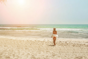 Happy traveller woman in white enjoys her tropical beach vacation