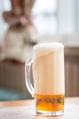 A mug of light, foaming beer on the table. the background is blurred bokeh. bright summer day