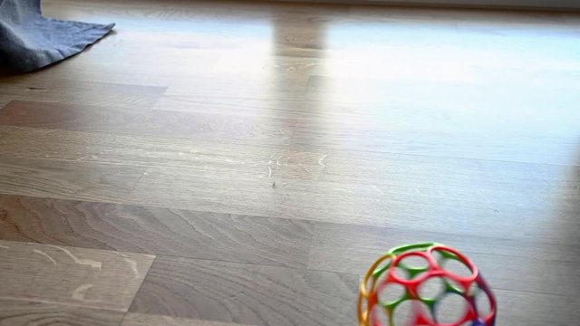 Colourful toy plastic ball spinning around over the floor in slow motion, stock footage by Brian Holm Nielsen