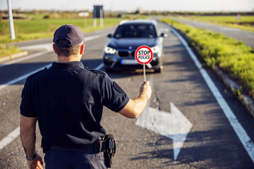 Police officer stops the car on the road.