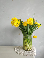 a bouquet of daffodils in a vase on a vintage table