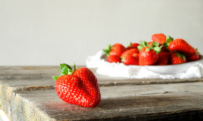 fresh strawberries on a wooden table, a plate with strawberries