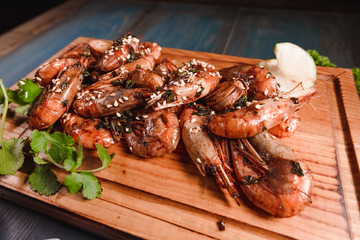 Appetizing fried prawns on a wooden tray among seasonings. Studio photography of food in the cooking industry, dark background