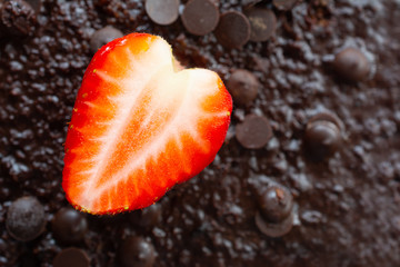 Top view of a half strawberry on chocolate background