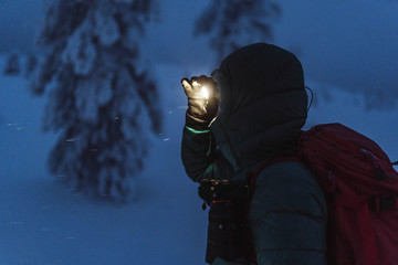 Trekker with a headlamp walking in a snowy Riisitunturi National Park, Finland