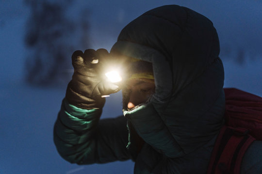 Trekker with a headlamp walking in a snowy Riisitunturi National Park, Finland