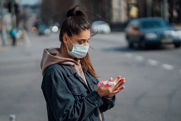 Caucasian girl disinfects her hands with sanitizing spray.