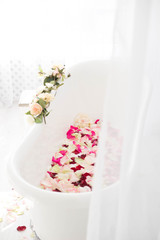 Fototapeta na wymiar White bath with rose petals