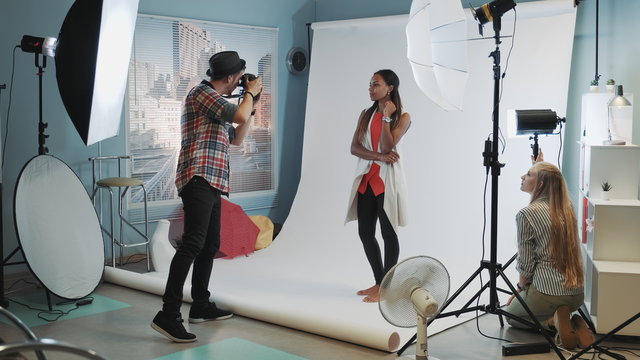 Photo session in modern studio: photographer taking photos of the black model an