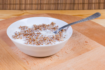 Buckwheat porridge with milk in the bowl with spoon