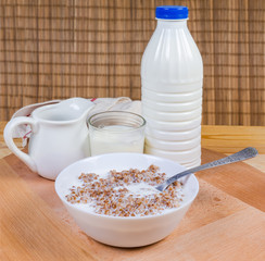 Buckwheat porridge with milk in bowl against the dairy products