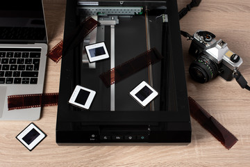 Photography digitalization process. A retro camera, transparencies, negatives, a scanner and a laptop.
