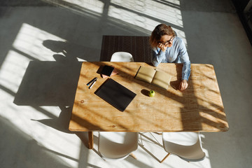 Student waiting for an online lesson. Bored, looking away. Bright room, long shadows