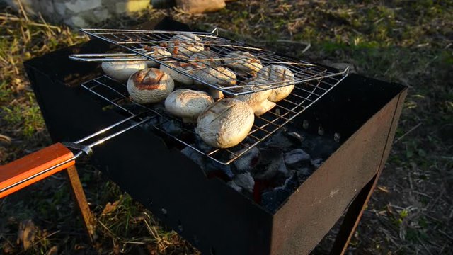 Man making BBQ mushrooms outdoors. 