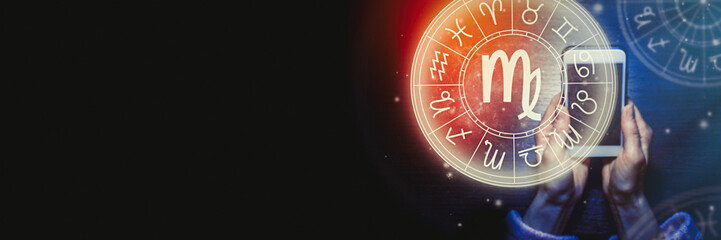 Female hands are holding a phone and an astrological circle with the zodiac sign Virgo against the background of the starry sky. Mobile Application for the horoscope. Banner. Copy space