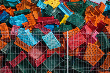 Old plastic boxes in a warehouse as a trash behind the metal mesh fence.