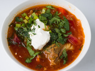 Borsch with sour cream in a white bowl on a white background. Close-up