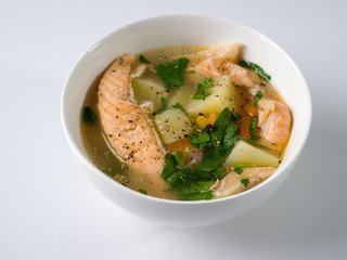 Fish soup in a white bowl. Salmon with potatoes and herbs. Side view