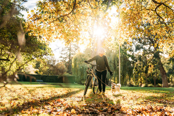 19/4/2020 Asian woman with a bike walking with a dog in autumn at the Botanic garden, Oamaru, New Zealand. Concept about exercise while social isolation from Coronavirus or Covid 19.