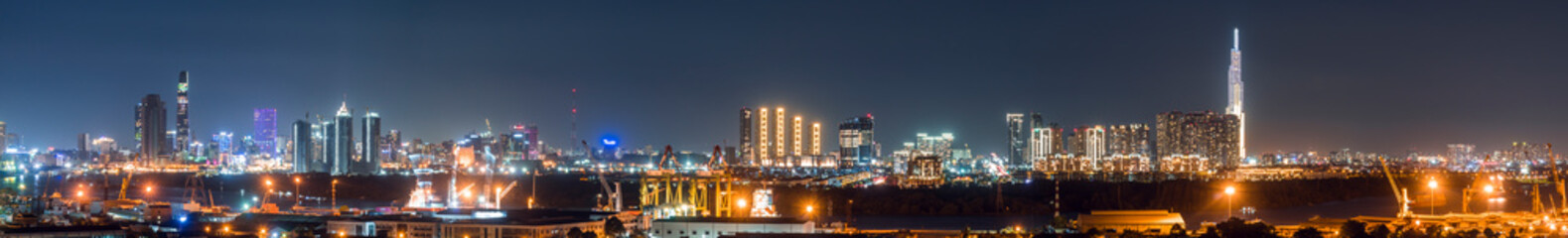 Fototapeta premium Urban night skyline panoramic view of Ho Chi Minh city. Ho Chi Minh City with development buildings, transportation, energy power infrastructure. View from District 7, Saigon. High resolution 