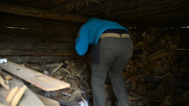 The old village in the Russian province. Man takes in an old barn firewood. 