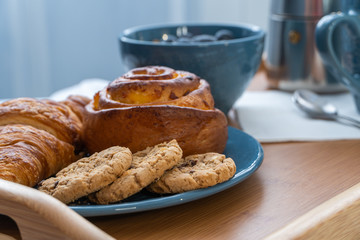 Breakfast served in bed on wooden tray with coffee and croissants