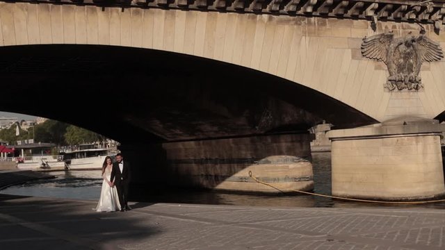 brides are walking under a bridge near the elven tower in paris